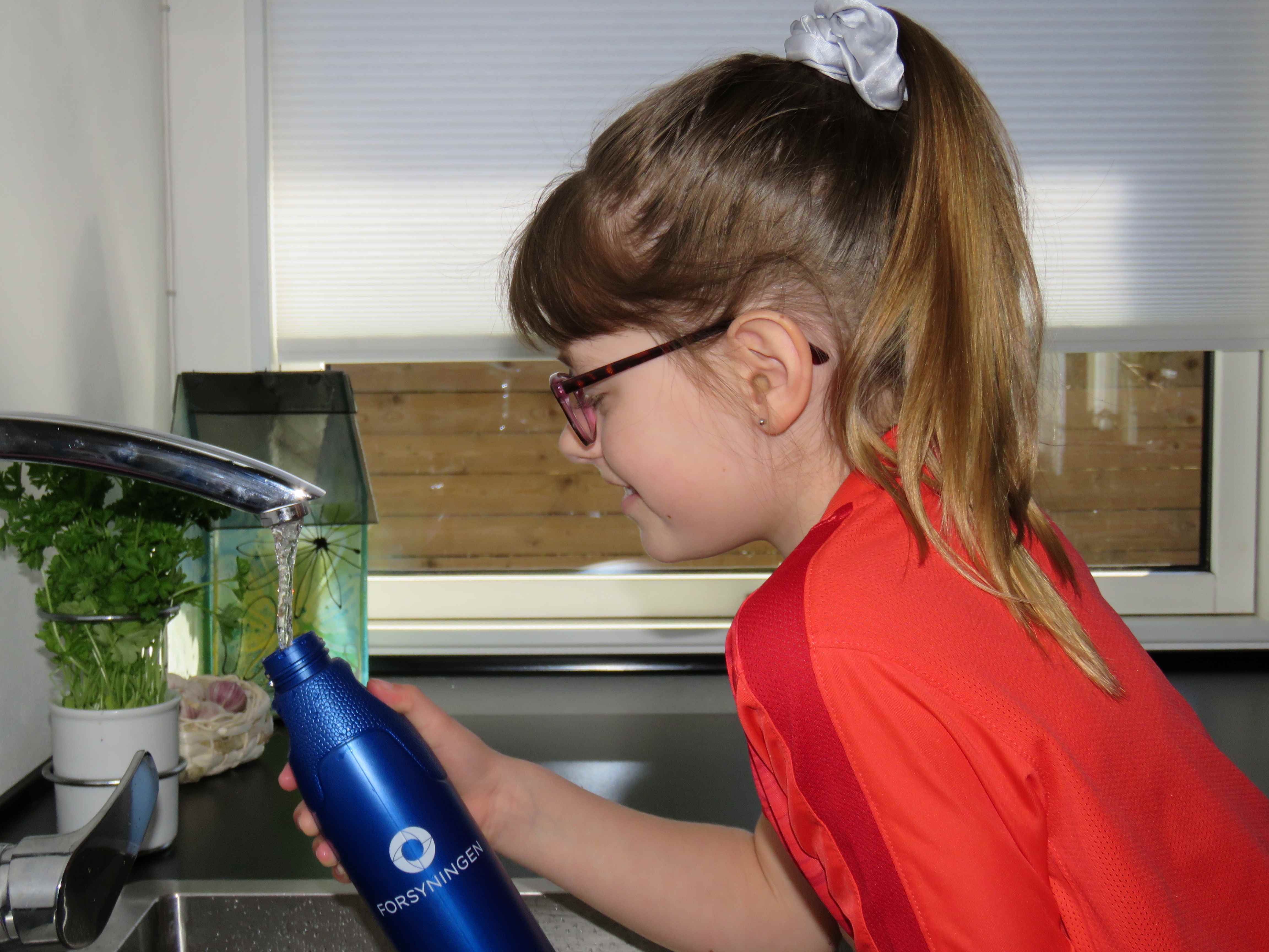 Barn ved vask fylder vandflaske op