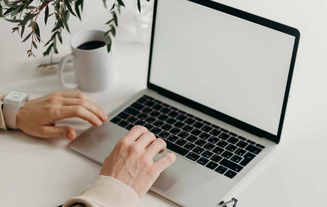 Kontorplads med bærbar, bog og kaffekop